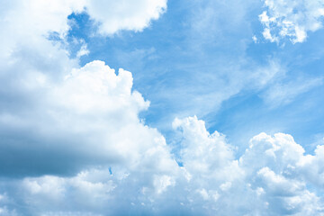 Fluffy white clouds drift across a bright blue sky, painting a breathtaking cloudscape