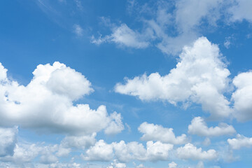 Beautiful fluffy white clouds drift across a bright blue sky