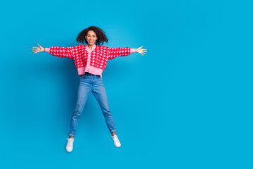 Portrait photo of american beautiful girl with curly hair wearing red shirt jumping star symbol isolated on blue color background