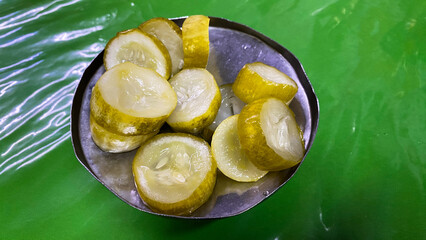 Marinated pickled cucumber slices on tin plate. Tasty pickled cucumbers on tin bowl 