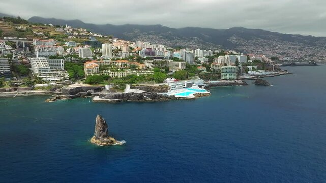 Aerial drone view of Funchal city with hotels resorts and swimming pool along the coast of Atlantic ocean. Funchal, Madeira, Portugal. Orbit parallax shot