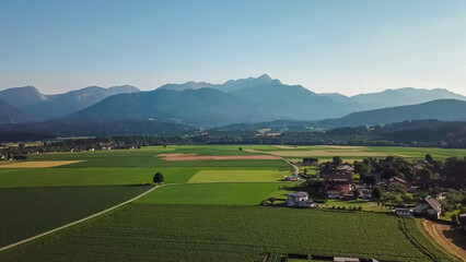 Vast field of crops in various stages of growth with scenic view of majestic mountain range of Karawanks seen from Rosental, Carinthia, Austria. Harvest time in rural Austrian Alps. Beauty in nature