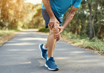 A person experiencing knee pain while jogging along a scenic park pathway on a sunny afternoon