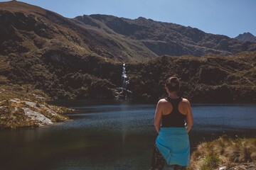 Woman by Mountain Lake and Waterfall