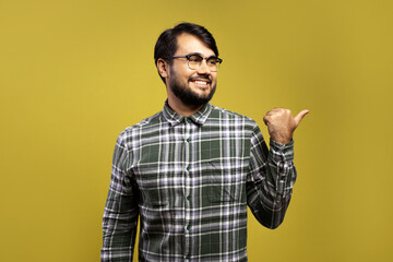 Naklejka premium man smiling, looking to the side and pointing with thumb