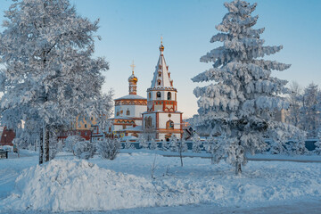 View of the Orthodox church on a winter day - icy branches and the sun