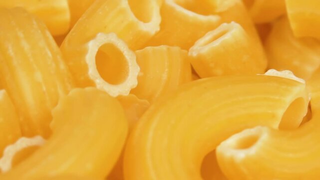 Uncooked Chifferi Rigati Pasta Rotating - Macro. Fat and Unhealthy Food - Close-Up. Classic Dry Macaroni. Italian Culture and Cuisine. Raw Golden Pasta