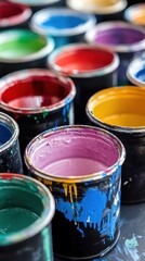 Vibrant paint cans in row with colorful drips