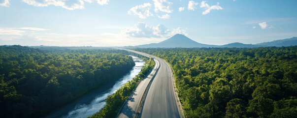 scenic highway surrounded by lush greenery and river, with mountain in background under clear blue sky. This tranquil landscape evokes sense of peace and adventure