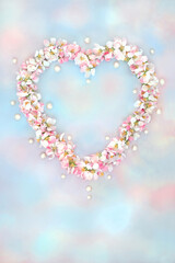 Heart shape Spring Beltane apple blossom flower wreath on abstract sky background with oyster...