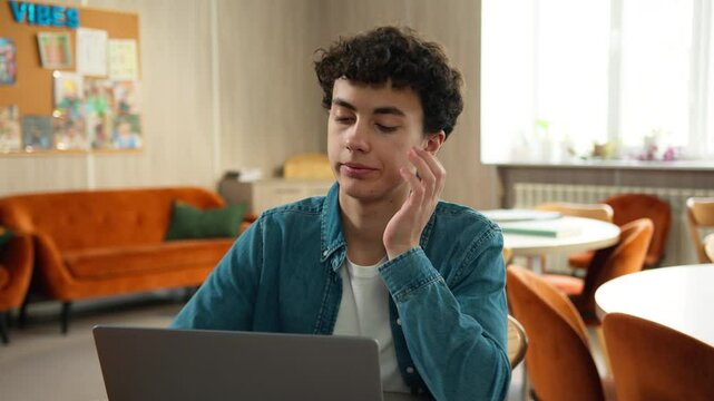 Stressed upset boring lazy Caucasian male boy teen exhausted fatigued Hispanic guy pupil man teenager e-learning studying online internet laptop computer homework at school university college boredom