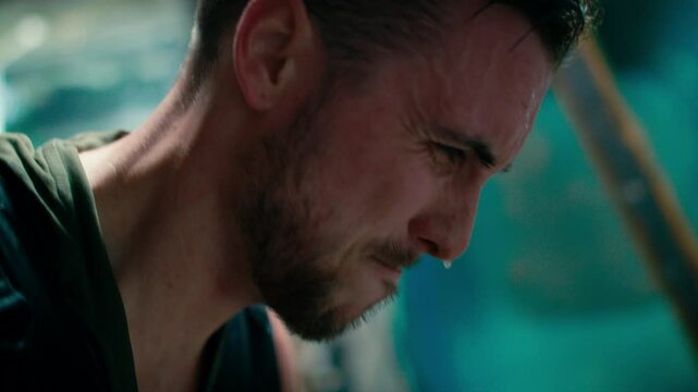 man's side portrait while he is working out and sweating with red face, against blur background