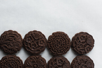 Overhead view of stamped chocolate cookies on a parchment lined baking tray, top view of embossed chocolate sugar cookies on a white background