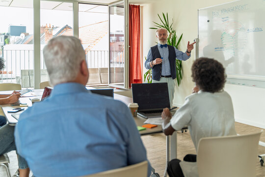 Senior doctor presenting pain management strategies, medical seminar, diverse healthcare team - Powered by Adobe