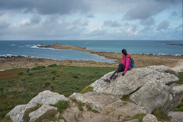 active senior woman cycling with her electric mountain bike at the rocky red granite cost next to Ploumanac'h,  Côtes d'Armor,Brittany, France