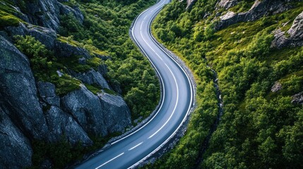 Winding asphalt road through green mountain valley with rocky cliffs.