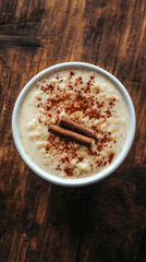 Creamy rice pudding with cinnamon in a white bowl on a rustic wooden table