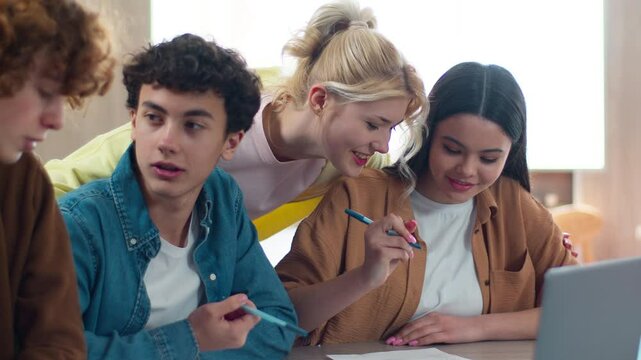 Four Caucasian students teens teenagers friends pupils male female boys guys girls women men studying together learning study e-learning education teamwork cooperate laptop at school writing homework