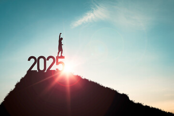 Silhouette of human standing on 2025 and the top of mountain blue sky and sunlight for start of new...