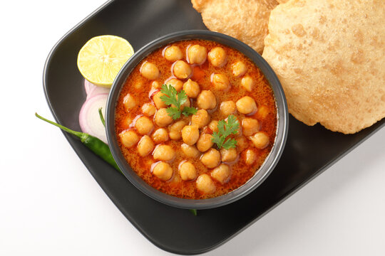 Chole Bhature or Chick pea curry with Fried Puri served in a ceramic plate and bowl