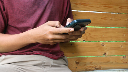 A man sits and types a message using a hand phone or smart phone. Social life in the age of technology.