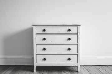 White Wooden Dresser with Black Knobs Against a White Wall