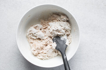 Bread dough being mixed in a ceramic bowl, Beet Focaccia dough in a white bowl, process of making pink focaccia