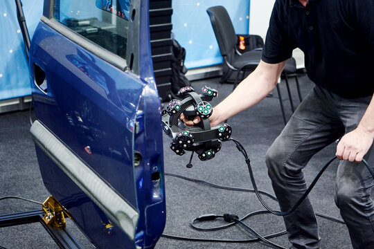 Engineer man with tracking 3D scanner and cars door