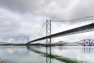 Panoramic view over the waters of the Firth of Forth at Queensferry, UK with three bridges, the cable stayed Queensferry Crossing, the Forth Bridge and the Forth Road Bridge near Edinburgh