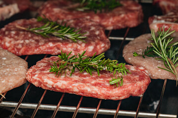 Juicy beef patties with fresh rosemary grilling on an oven rack