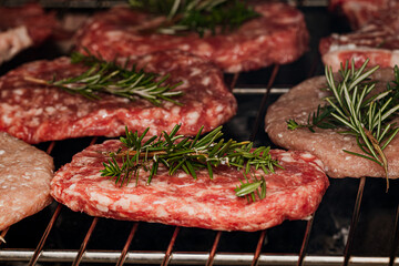Juicy beef patties with fresh rosemary grilling on an oven rack