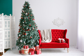 White Interior with white walls and red soft sofa decorated for celebrating New Year. Comfort home in Christmas Holidays	