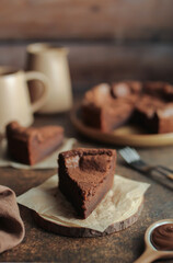 Flourless Chocolate Cake. Brown background. Orange cup and milk jug.