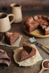 Flourless Chocolate Cake. Brown background. Orange cup and milk jug.