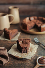 Flourless Chocolate Cake. Brown background. Orange cup and milk jug.