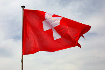 The Swiss flag waving in a cloudy sky