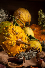 Close-up of yellow pumpkin with autumn leaves and nuts, on wooden table, vertical, with copy space