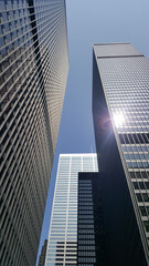 Glass, concrete and metal skyscrapers with a bright glare of sun on the window and a blue sky in the background 