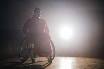 Young beautiful woman in a red dress dancing in a wheelchair, enjoying elegant graceful movements...