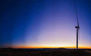 a mesmerizing sunset scene with wind turbines spread across a landscape