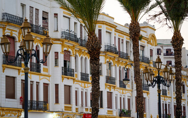 Beautiful colonial facade In Tangier, Tanger, Morocco. white, yellow. Street lamp. Palm trees.