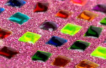 Closeup of colorful crystal gems on pink glitter surface, vibrant macro detail of sparkling...
