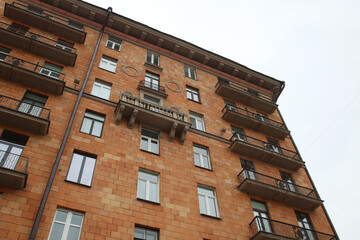 I am looking up at a very large brick building that features balconies