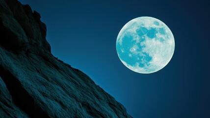 Naklejka premium A vibrant full moon illuminates a rocky landscape under a deep blue sky, creating a serene nighttime atmosphere.