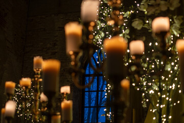 Elegant candlelit setting with twinkling fairy lights and adorned windows during twilight hours in a grand venue