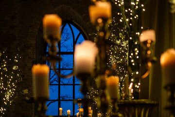 Elegant candlelit decor illuminates a stunning interior with a large window at twilight, surrounded...