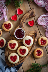 Romantic dessert for breakfast: Cookies with jam in the shape of a heart. Sweet cookies for a romantic breakfast on a wooden background. Cookies for a loved one. Vertical photo. Close-up