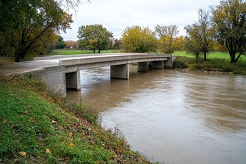 Fototapeta premium A concrete bridge spanning a calm river, blending into the soft gray landscape