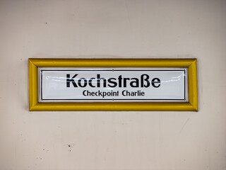 Kochstraße sign at the underground train station in Berlin Kreuzberg, Germany. Location name of the public transportation. White wall with black letters on white. Checkpoint Charlie as destination.