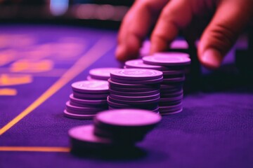 Strategic hand arranging casino poker chips on purple table